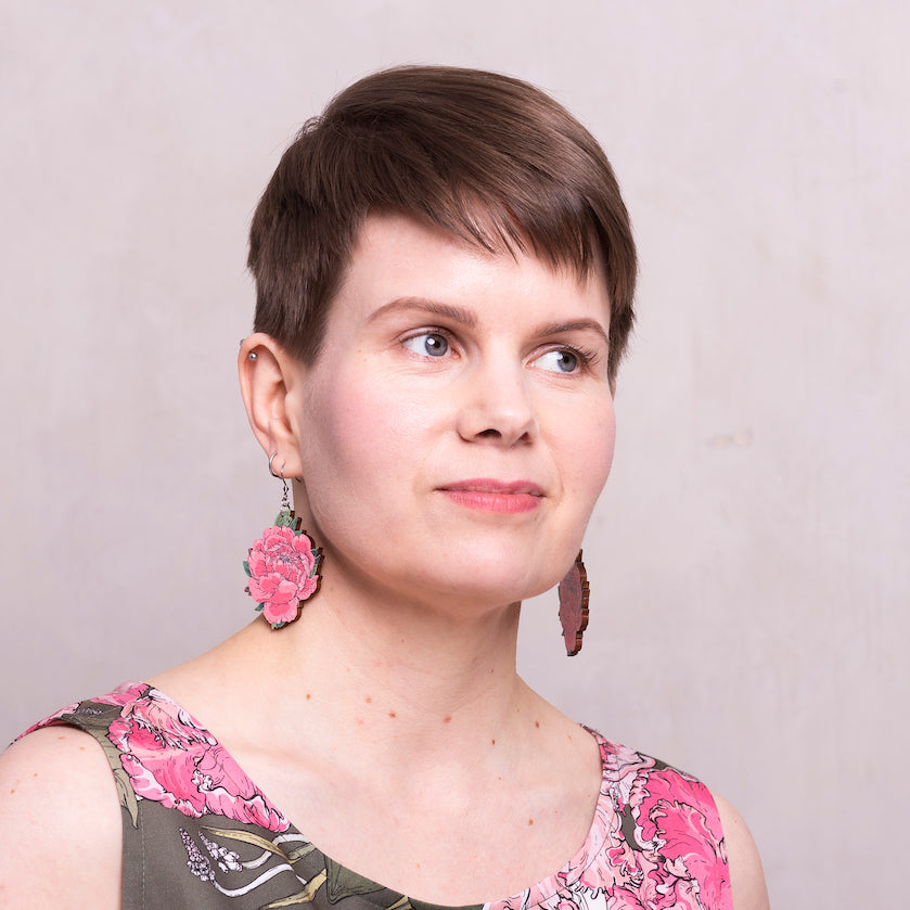 Headshot of a woman with brown hair and floral tank stop wearing pinkish red wooden peony earrings.