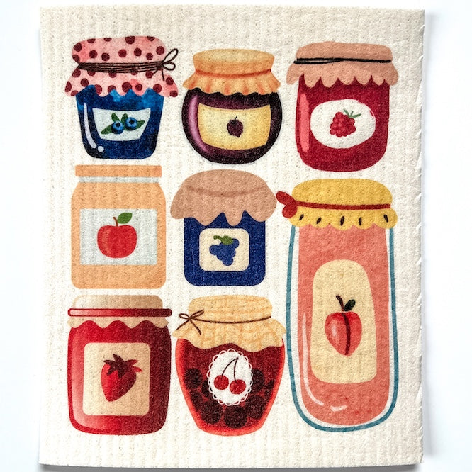 Dishcloth with an illustration of a hanging green cylindrical bird feeder with cardinals and other birds in yellows, reds, oranges and black on a gray background with hay colored branches.