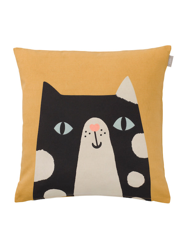 Mustard yellow pillow cover with an illustration of a large face of black cat with white spots, muzzle, light blue eyes and pink heart nose.