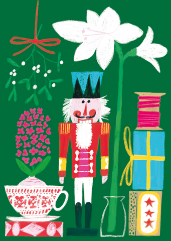 Green background with colorful nutcracker front and center between a white amaryllis and a pink hyacinth in teacup. Mistletoe hangs in the upper left corner and a stack of gifts and pink thread on a wooden bobbin sit in the lower right corner.