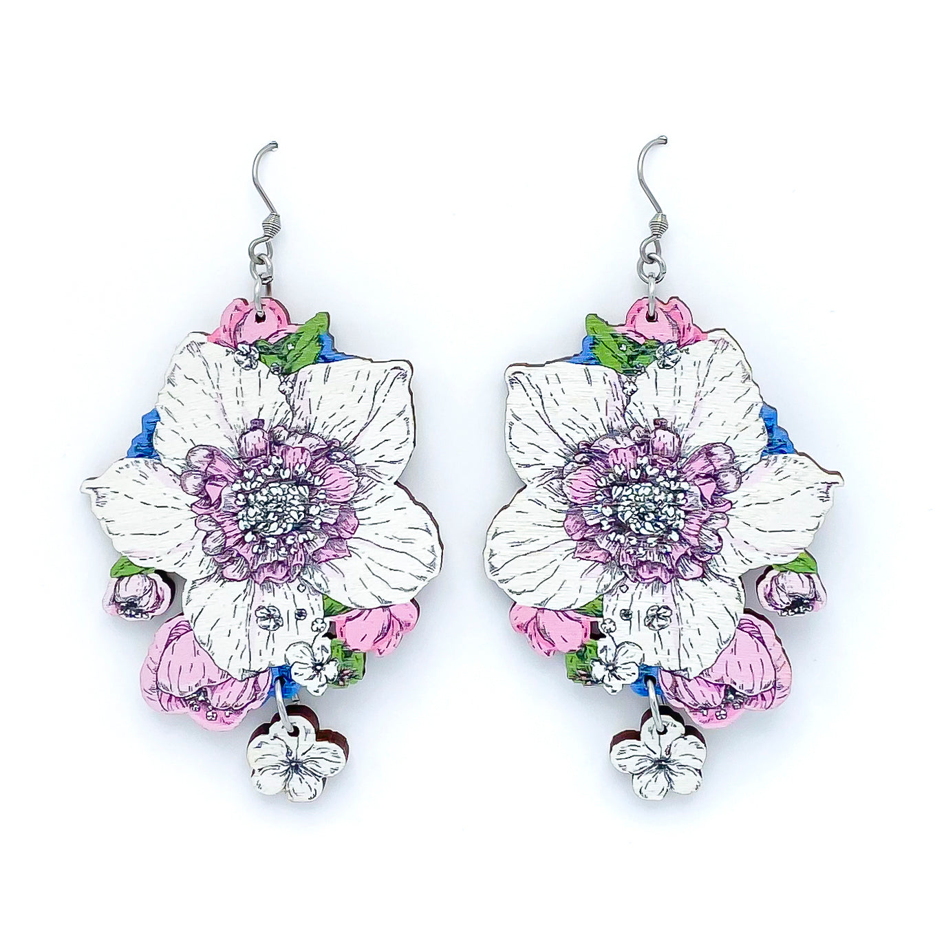 Photo of colorful wooden earrings on a white background. The main flower is white with pink center surrounded by smaller blue, pink and white flowers.