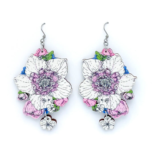 Photo of colorful wooden earrings on a white background. The main flower is white with pink center surrounded by smaller blue, pink and white flowers.